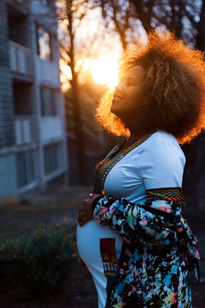 Pregnant woman enjoys sunset glow, embracing nature's serenity.